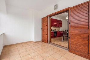 A room with a wooden door leading to a kitchen with red cabinets and a tiled floor. - Budoni Beach Homes, Budoni, Italy (Budoni)