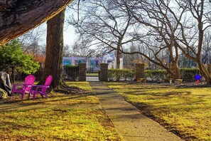 Ein Park mit einem gepflasterten Weg, einem Baum und zwei rosafarbenen Stühlen.
