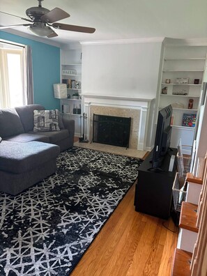 Un salon avec un canapé, un tapis à motifs, une cheminée et un téléviseur.
