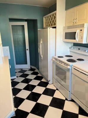 A kitchen with a checkered floor, a refrigerator, a microwave, and a stove. - 2BR Condo by Airport and Downtown Cbus (Columbus)