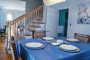 Un coin repas avec une nappe bleue, des chaises en bois et un lustre.
