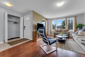 Een woonkamer met een blauwe fauteuil, een bank, een salontafel en een televisie.