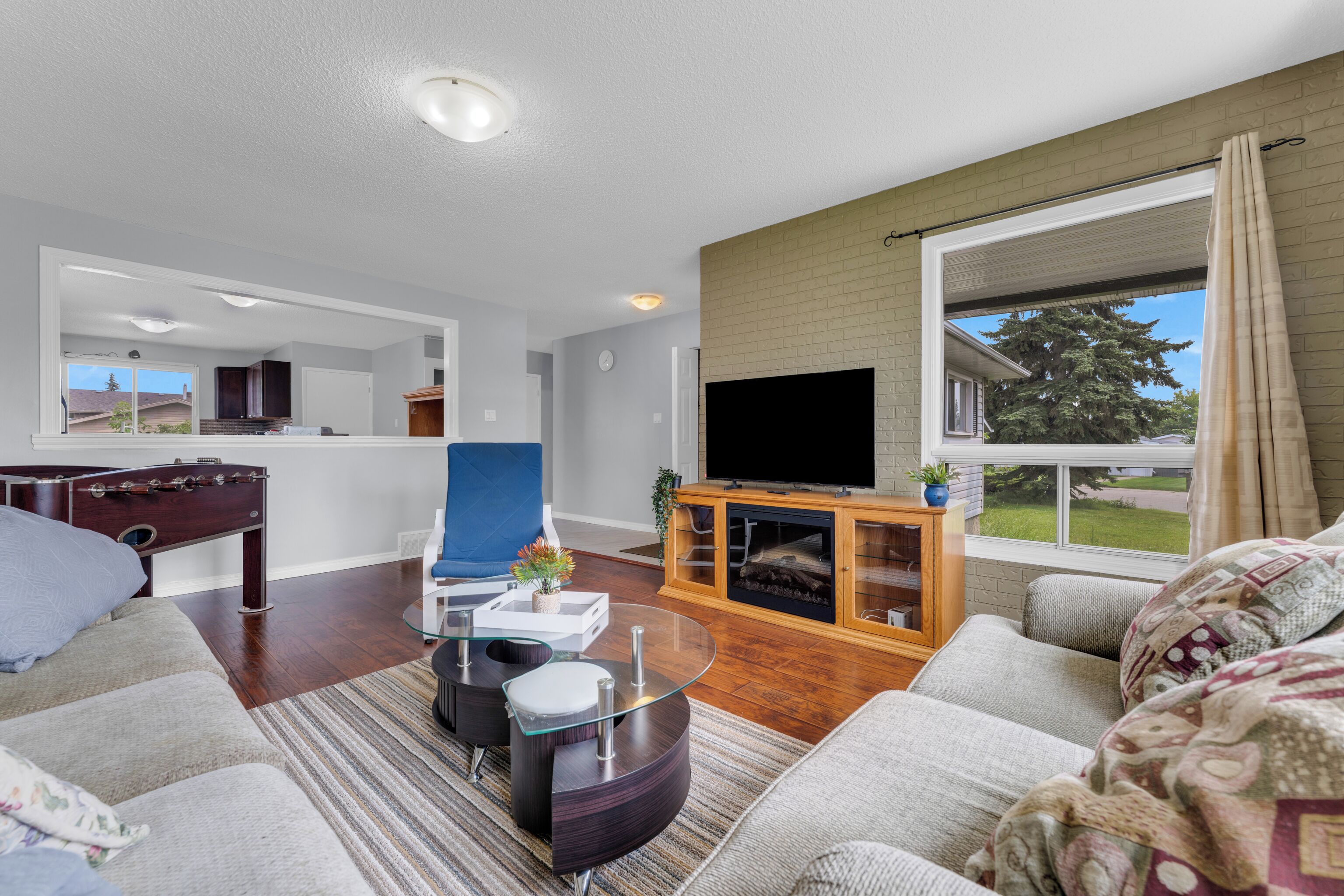 A modern living room with a flat-screen TV, a sofa, a coffee table, and a fireplace.