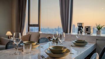 A dining table set with bowls, glasses, and cutlery in a modern interior with a city view.