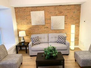 Ein Wohnzimmer mit Backsteinwand, zwei Sofas, einem Couchtisch und einer Lampe.