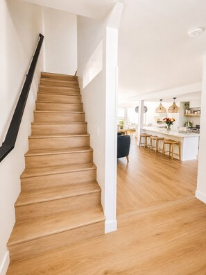 A staircase leading to a kitchen area with wooden flooring and a white interior. - Stylish Newport Beach Retreat Walk to Beach & Lido (Newport Beach)