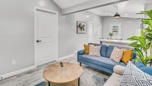 A modern living room with a blue sofa, a round coffee table, and a large plant. - Cozy Blue Cottage Near Old Town Monrovia, City of Hope. Pet-Friendly (Monrovia)
