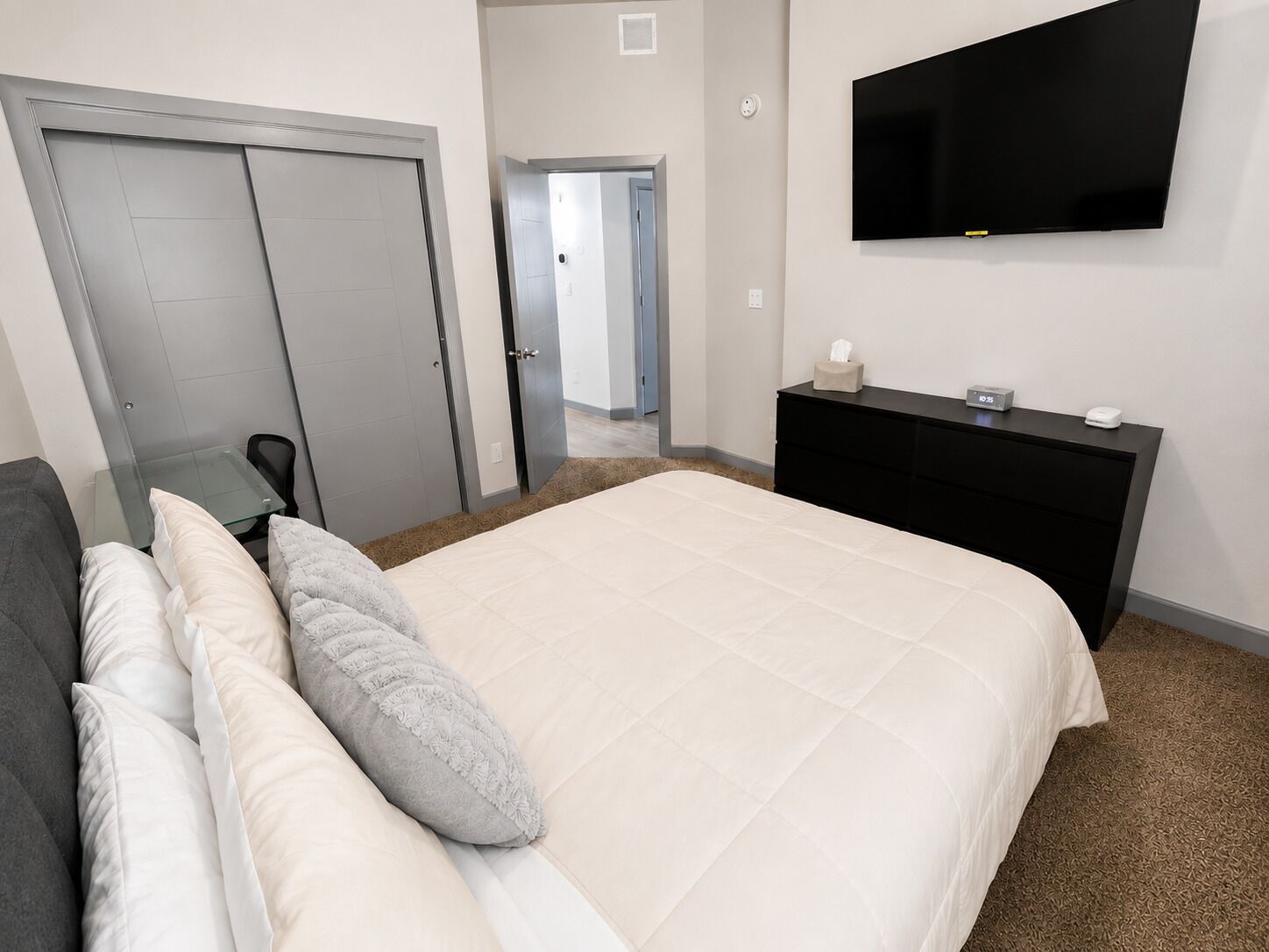 A hotel room with a bed, a TV mounted on the wall, a desk, and a wardrobe.