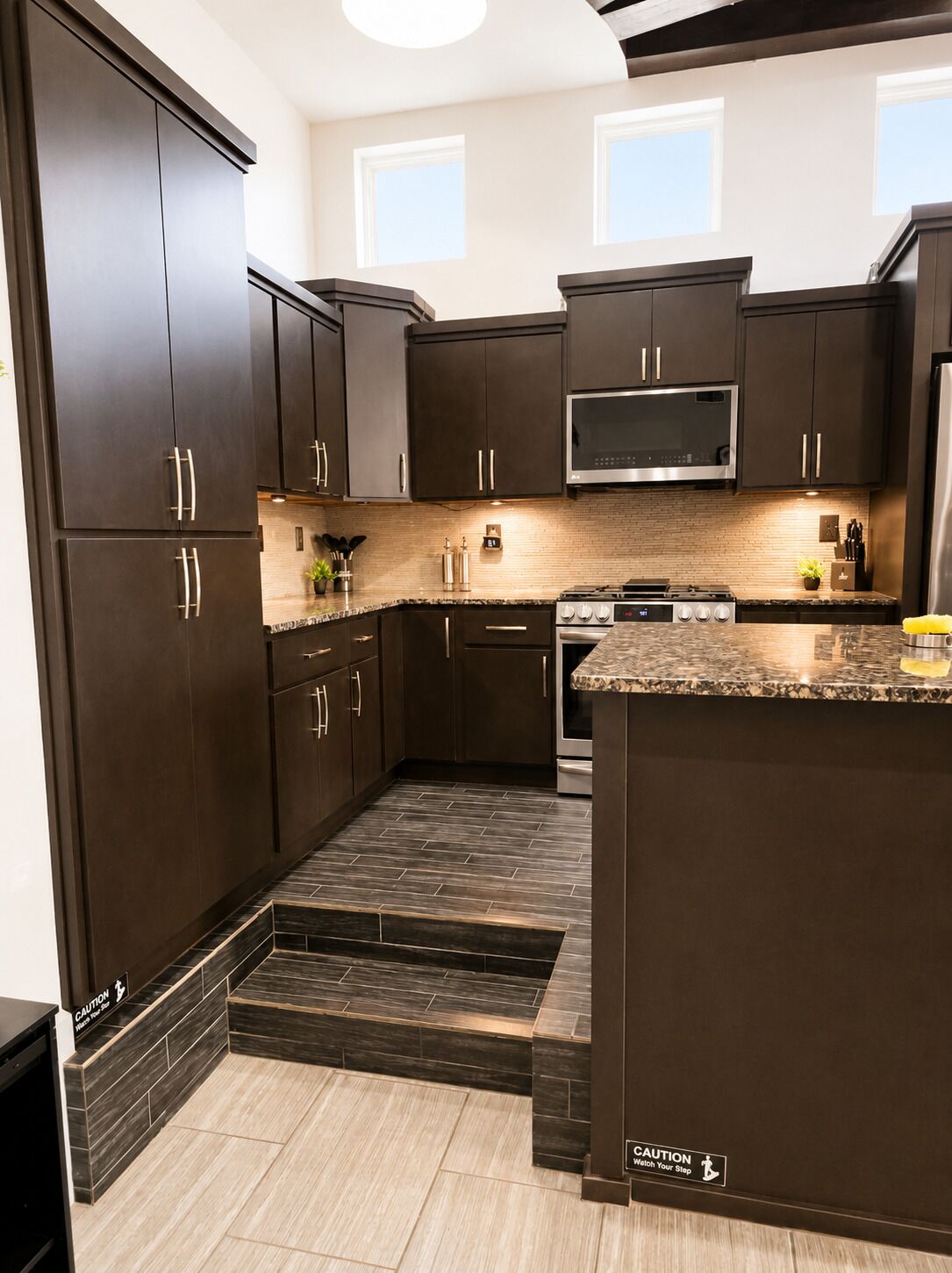 A modern kitchen with dark cabinetry, a microwave, and a gas stove.