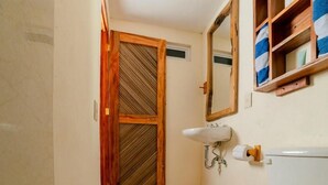 A bathroom with a wooden door, a sink, and a toilet. - Cabaña Paraguitos (Brisas de Zicatela)