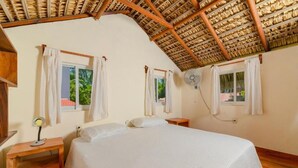 A bedroom with a bed, two bedside tables, a ceiling fan, and windows with curtains. - Cabaña Paraguitos (Brisas de Zicatela)