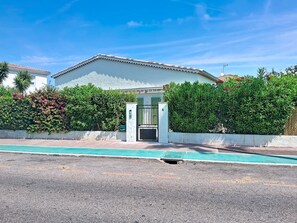 A residential building with a gated entrance, a swimming pool in the foreground, and a clear blue sky. - Villa l'Orangeraie by Interhome (Villeneuve-Loubet)