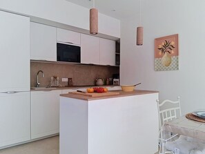 A modern kitchen with white cabinets, a central island, and pendant lighting. - Villa l'Orangeraie by Interhome (Villeneuve-Loubet)