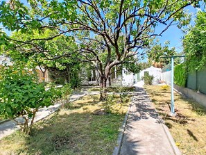A pathway flanked by trees and a fence, leading to a building with a white facade. - Villa l'Orangeraie by Interhome (Villeneuve-Loubet)
