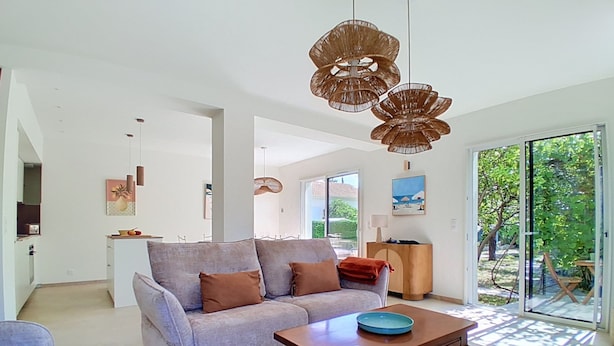 A modern living room with a sofa, a wooden coffee table, and a dining area with a table and chairs. - Villa l'Orangeraie by Interhome (Villeneuve-Loubet)