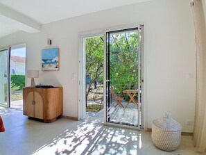 Habitació amb una porta corredissa de vidre que dona a una zona exterior, un armari de fusta i un quadre a la paret.