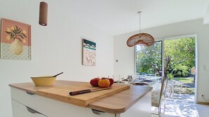 A modern kitchen with a wooden countertop, white cabinets, and a view of the outdoors through a glass door. - Villa l'Orangeraie by Interhome (Villeneuve-Loubet)