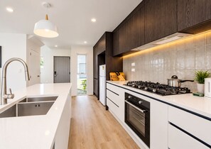 A modern kitchen with a central island, stainless steel appliances, and a view to the outside. - Modern Central Auckland Stay- perfect for families, groups & business travellers (Mt Roskill)