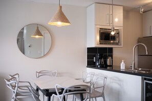 Een moderne keuken met witte kasten, een ronde spiegel en hanglampen.