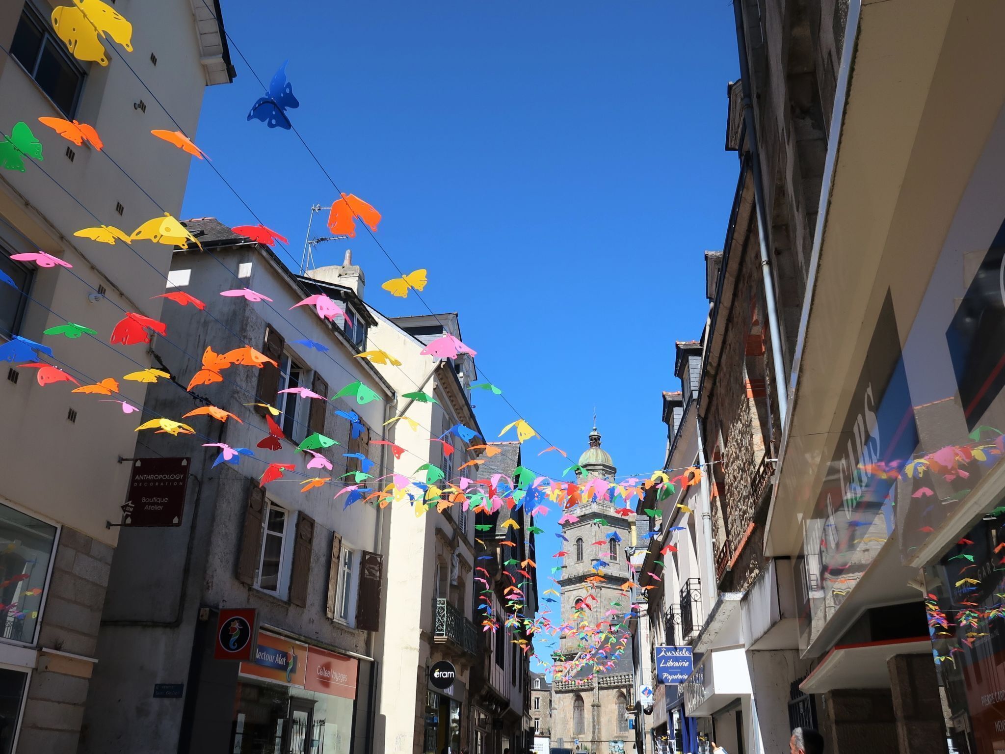 A narrow street lined with buildings, some with visible signage for shops and services.