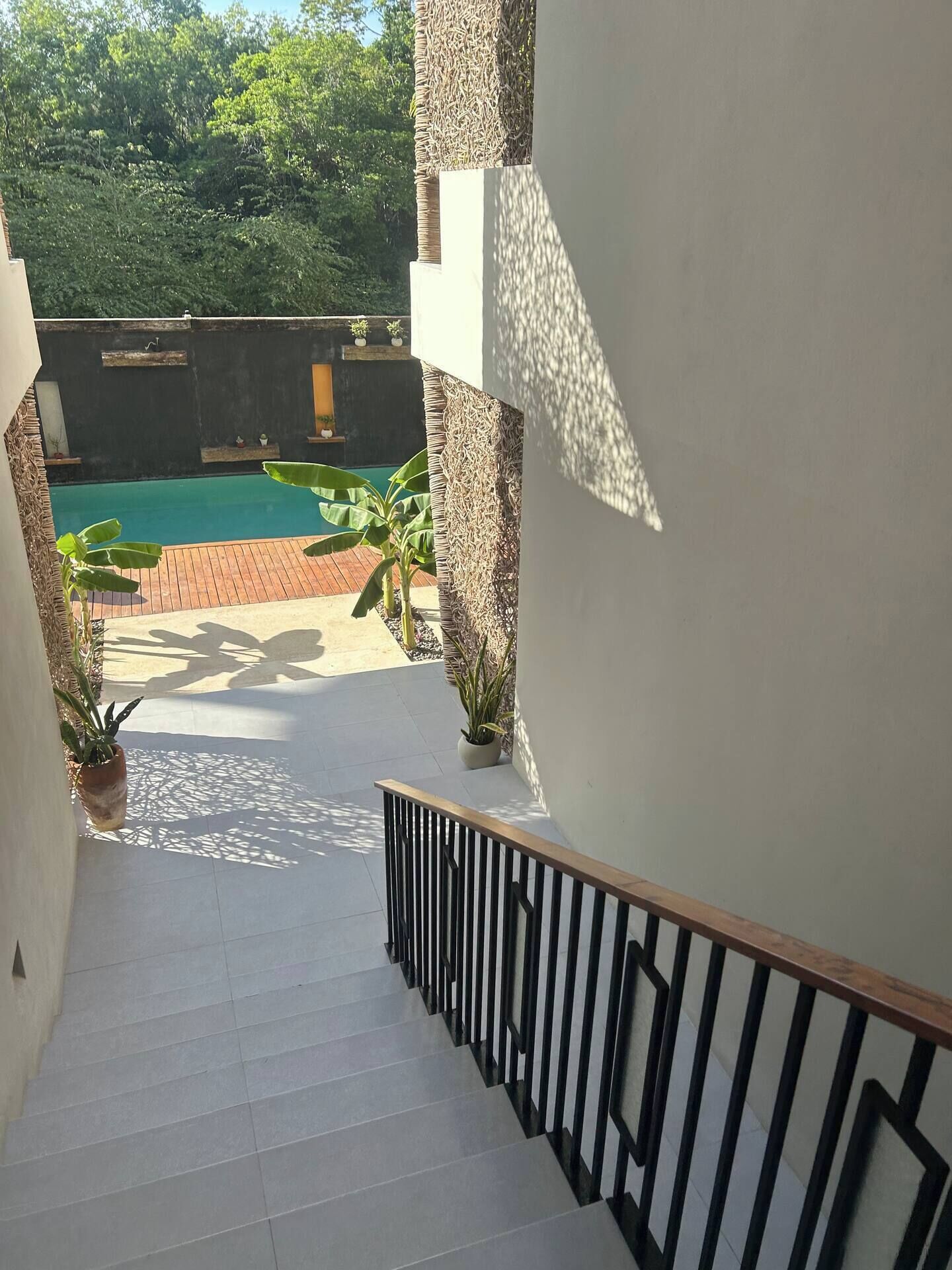 Escada que leva a uma área de piscina com vista para um jardim e uma piscina.