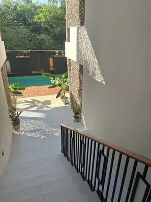 Eine Treppe führt zu einem Poolbereich mit Blick auf einen Garten und ein Schwimmbecken.
