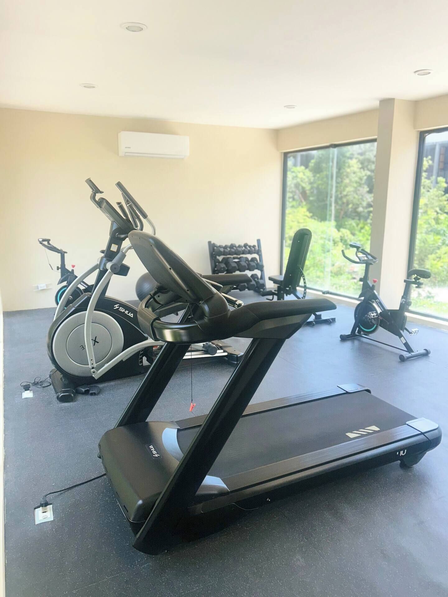A gym with exercise equipment including a treadmill and stationary bikes.