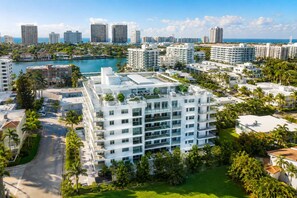 A high-rise hotel with multiple balconies, a marina in the background, and a clear view of the ocean. - Chic Bay Harbor 3BR • Rooftop Pool • Free Parking (Bay Harbor Islands)