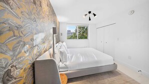A bedroom with a bed, a window, a wardrobe, and a wall with a floral pattern. - Chic Bay Harbor 3BR • Rooftop Pool • Free Parking (Bay Harbor Islands)