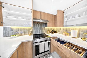 A modern kitchen with wooden cabinets, stainless steel appliances, and integrated lighting. - Chic Bay Harbor 3BR • Rooftop Pool • Free Parking (Bay Harbor Islands)
