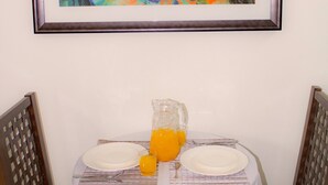 Ein Esstisch mit zwei Tellern, einem Saftkrug Orangensaft und einem gerahmten abstrakten Gemälde an der Wand.