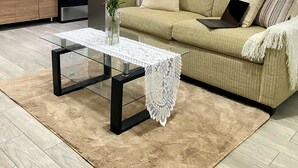 Ein modernes Wohnzimmer mit einer Couch, einem Couchtisch und einer Küchenzeile mit Geräten.