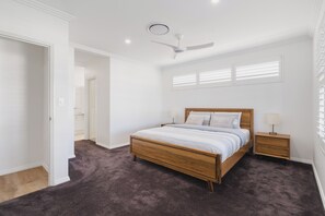 Una camera da letto con un letto di legno, un comodino, una ventola a soffitto e una finestra con persiane.