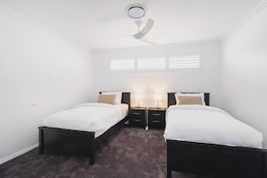A bedroom with two single beds, a ceiling fan, and a window with blinds. - Canal Living with a Private Jetty (Geographe)