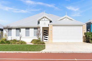 A single-story house with a garage, a small front yard, and a clear sky. - Canal Living with a Private Jetty (Geographe)