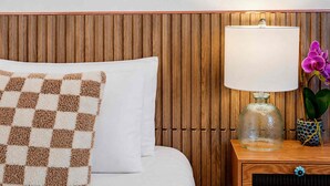 A neatly made bed with a checkered throw pillow, a bedside lamp with a clear glass shade, and a vase with a purple orchid. - Stargazing Giant Hammock/Heated Pool/Spa (Largo)