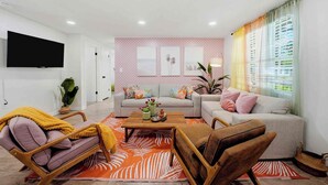 A modern living room with a flat-screen TV, a sofa set, a coffee table, and a large window with curtains. - Stargazing Giant Hammock/Heated Pool/Spa (Largo)