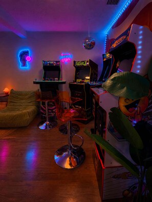 Une salle avec des jeux d’arcade, un néon et une boule à facettes.