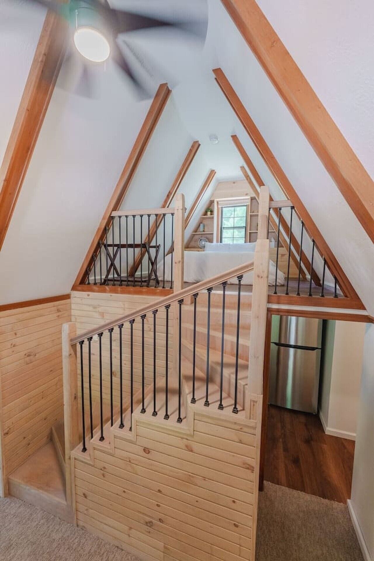 Eine Holztreppe mit Metallgeländer, die zu einer oberen Ebene führt.