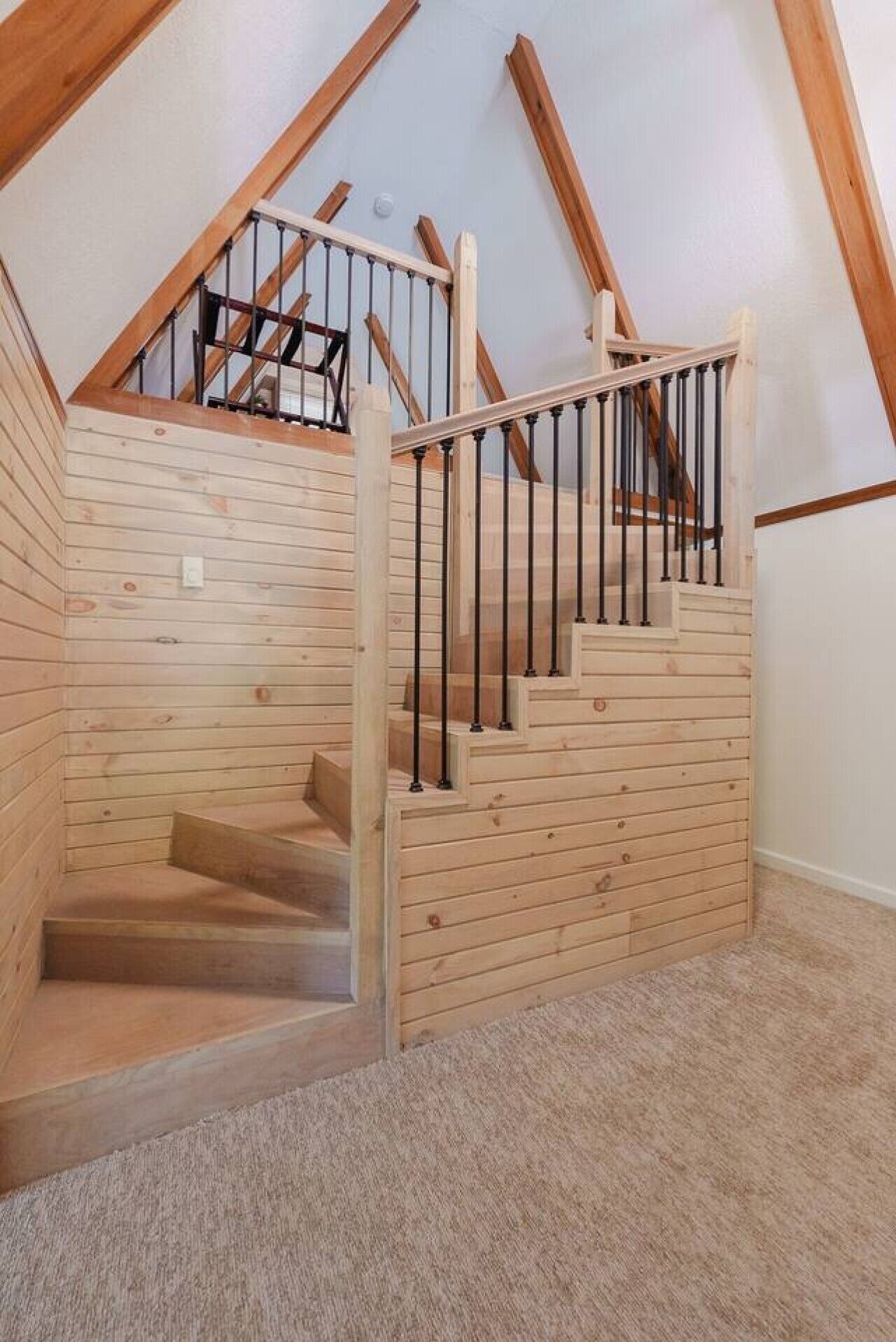 Un escalier en bois, protégé par une paroi de verre, mène à un niveau supérieur.