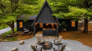 Eine Hütte mit Kamin, Sitzgelegenheiten im Freien und einer Kiesterrasse.