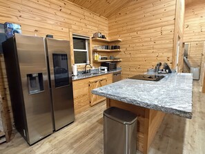A compact kitchen with wooden walls, stainless steel appliances, and granite countertops.