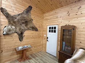 Una habitació amb parets de fusta, un pell de preses penjada, una porta i un armari.