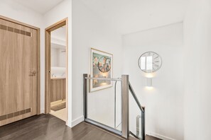 Um interior moderno com uma porta de madeira, uma obra de arte emoldurada e um relógio fixado na parede.
