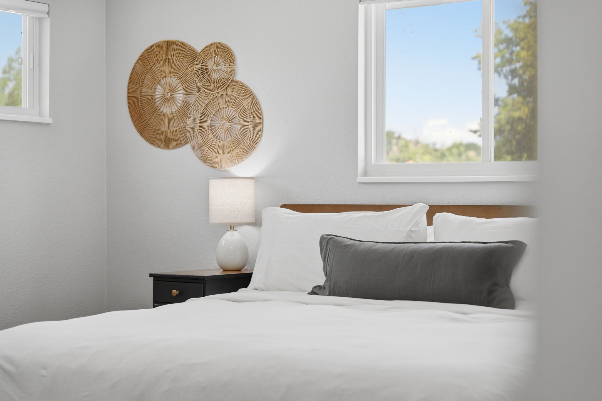 A neatly made bed with white linens, a bedside lamp, and a decorative wall piece.