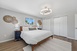 Ein Schlafzimmer mit einem Bett, Nachttischen, einem Fenster und einem Deckenventilator.