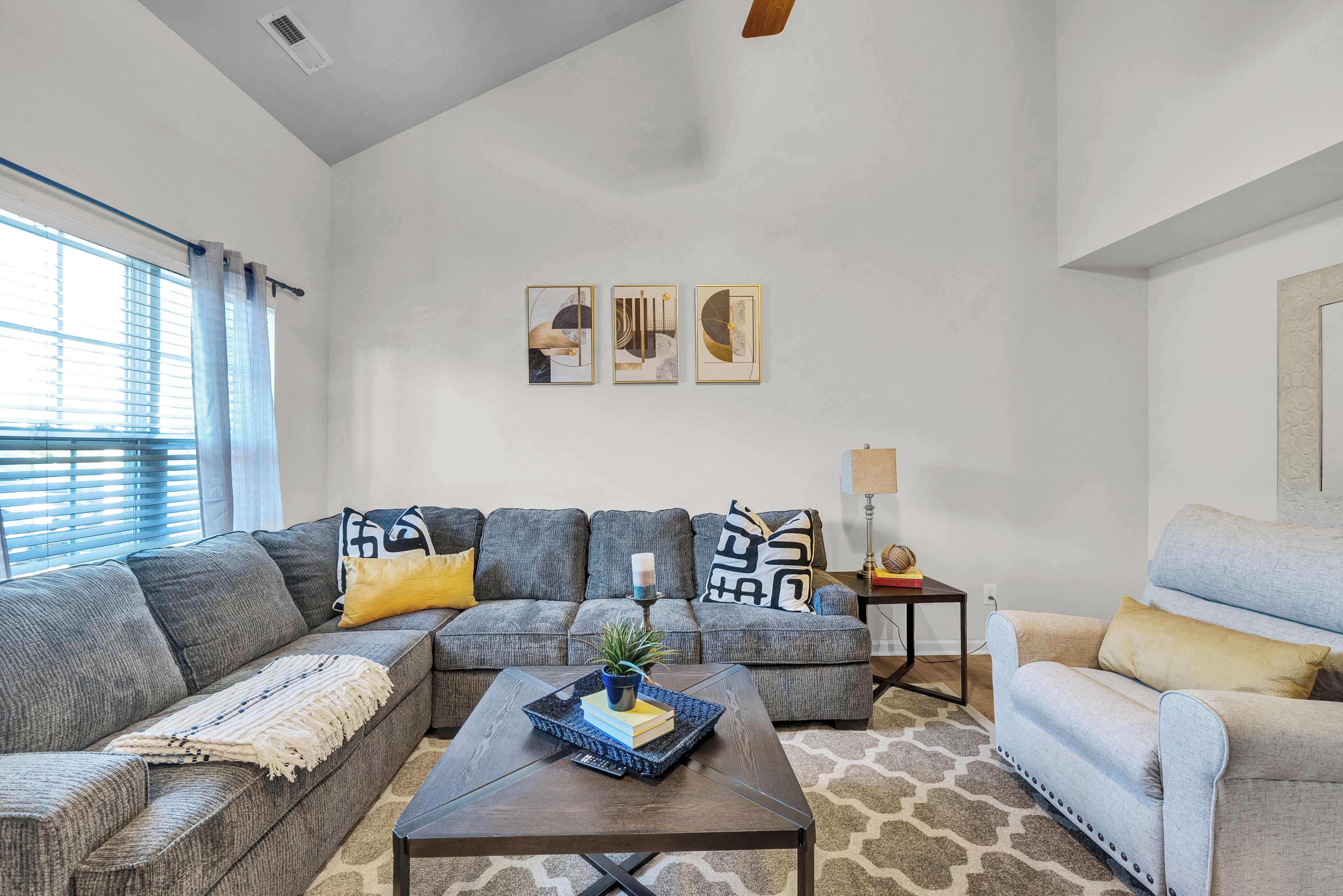 A modern living room with a sectional sofa, a coffee table, and a side table with a lamp.