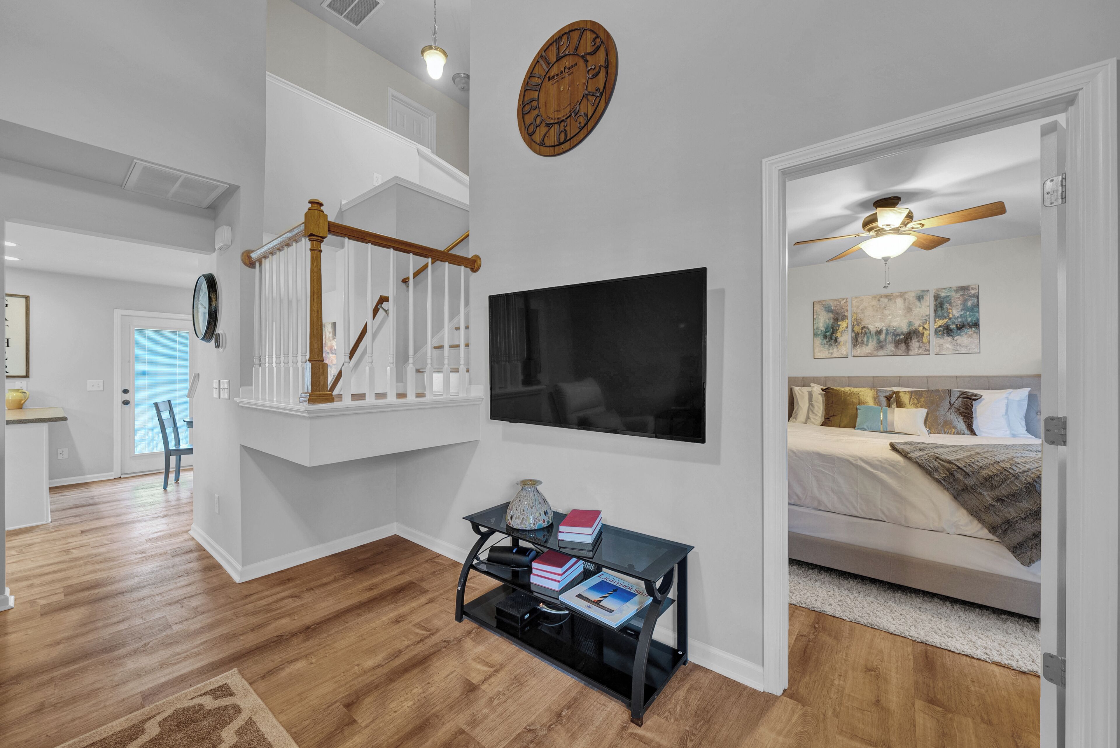 A modern interior with a staircase, a flat-screen TV, a bed, and a ceiling fan.