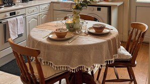 Una cocina con una mesa de comedor para dos, una ventana que ofrece vistas a una casa y una lavadora.