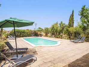 A swimming pool with lounge chairs and umbrellas, surrounded by greenery. - S'Hort den Vadell by Interhome (Campos)